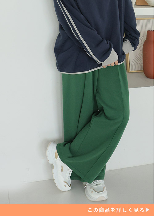 ネイビーのトレーナーにグリーンのスウェットパンツを履く女性