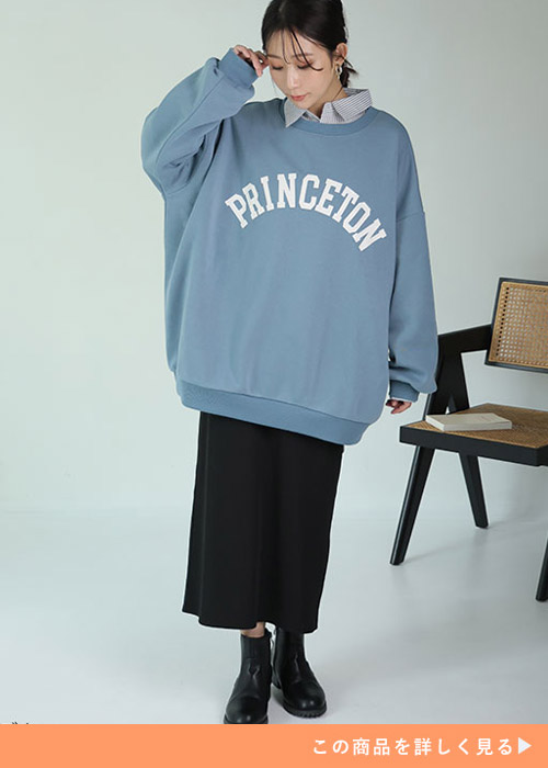 黒のタイトスカートにブルーのロゴトレーナーを着る女性