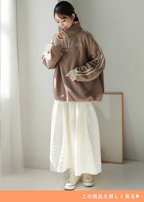 白のスカートにブラウンのジップスウェットを着る女性