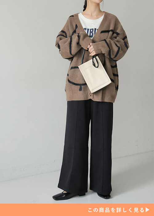 黒のパンツに白T、ブラウンのカーディガンを羽織った女性