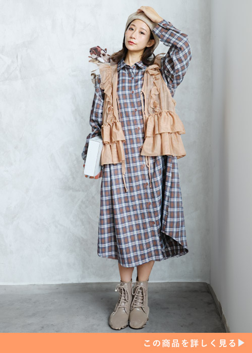 ブラウン系チェックのロングシャツにフリルショートベストを合わせる女性
