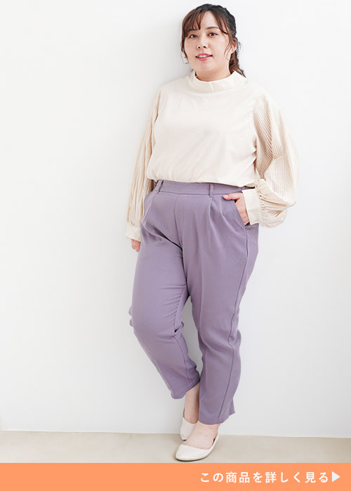 ライラックのテーパードパンツとホワイトベージュのブラウスのコーデにパンプスを履く女性