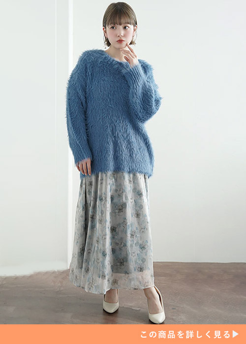 花柄のスカートとブルーのふわふわニットトップスのコーデにホワイトパンプスを履く女性