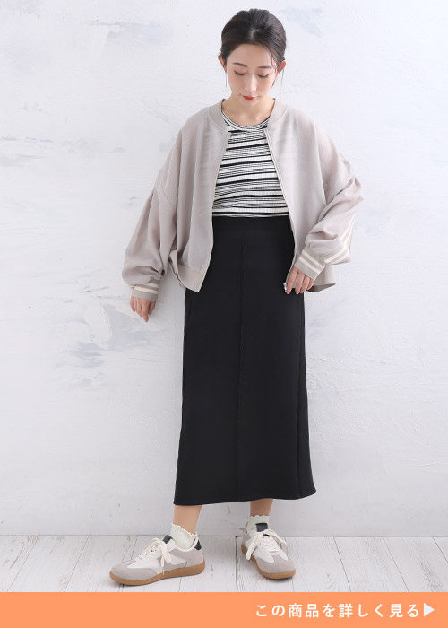 ブラック系ボーダートップスとブラックタイトスカートのコーデにベージュブルゾンを羽織る女性