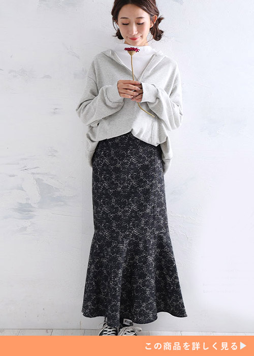 ホワイトインナーと花柄ブラックのペプラムスカートのコーデにカーディガンを羽織る女性