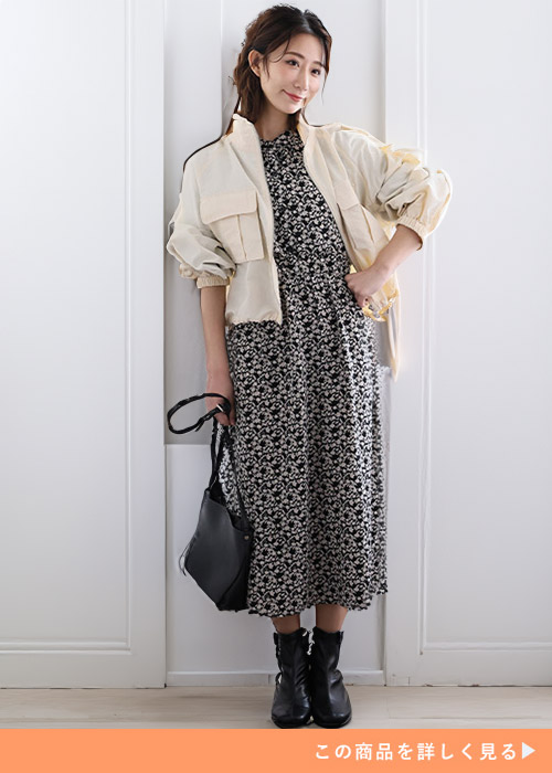 ブラックの小花柄ワンピースにショートブルゾンを羽織りブラックショートブーツを履く女性