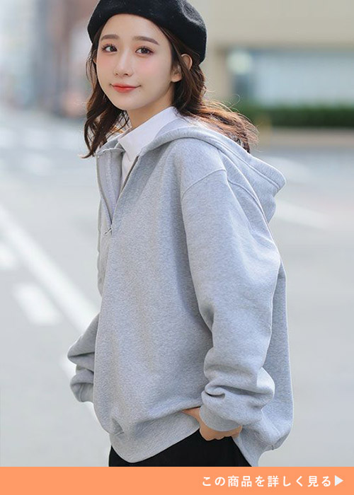 グレーのハーフジップパーカーを着る女性