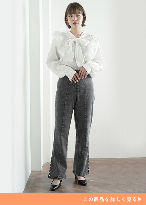 リボンタイ付き白ブラウス×裾パールのブラックデニムを着る女性