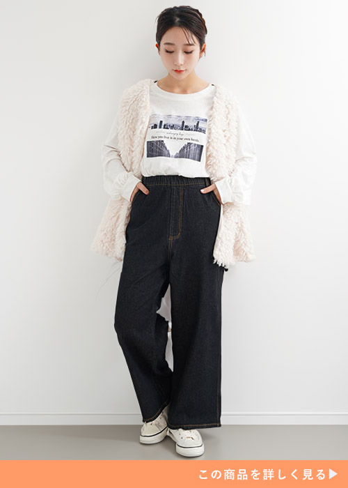 白のロンT×黒デニムのペインターパンツを着て、ピンクのファーベストを羽織る女性