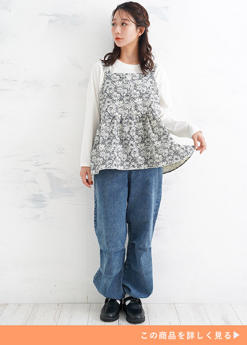 白のロンT×花柄のフレアチュニックを着て、パラシュートデニムパンツをはく女性