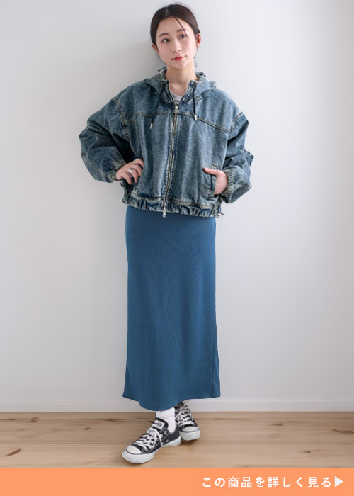 デニムのマウンテンパーカを着て、ブルーのナロースカートをはく女性