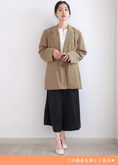 ホワイトブラウスとブラックスカートのコーデにベージュのテーパードジャケットを羽織る女性