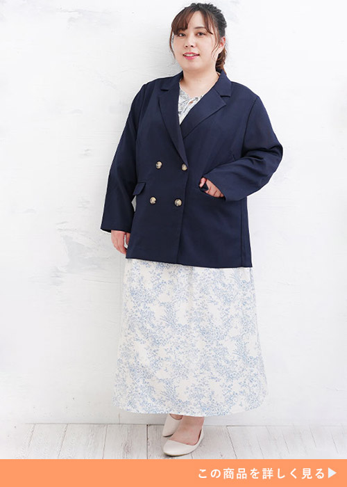 ネイビーのダブルボタンジャケットと花柄のスカートのコーデにホワイトパンプスを履く女性