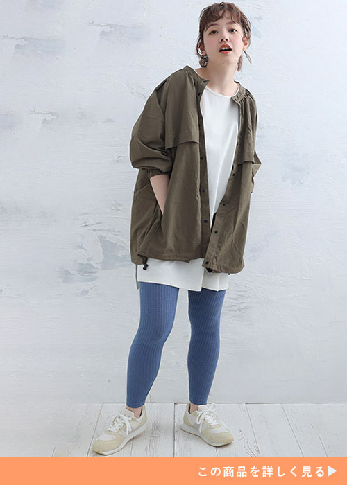 ホワイトトップスとブルーのレギンスのコーデにカーキのジャケットを羽織る女性