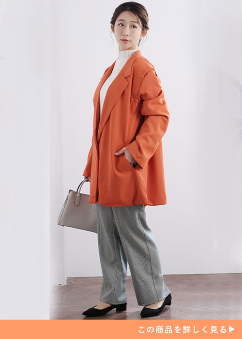 ホワイトトップスとグレーパンツのコーデにアラゴンオレンジのジャケットを羽織る女性