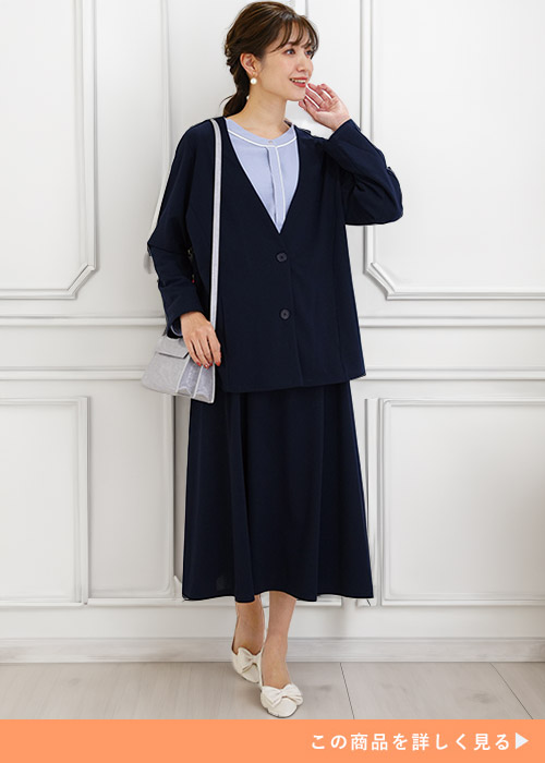 ブラックのジャケットとスカートのセットアップにホワイトパンプスを履く女性