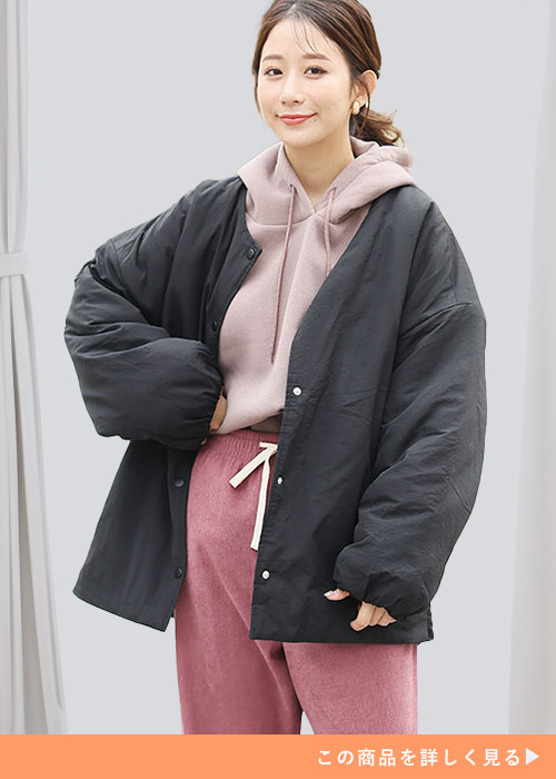 ローズカラーのパーカとパンツのコーデにチャコールの中綿ジャケットを羽織る女性