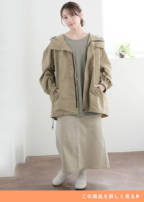 グレーのトップスとベージュのスカートのコーデにベージュのマウンテンパーカを合わせる女性