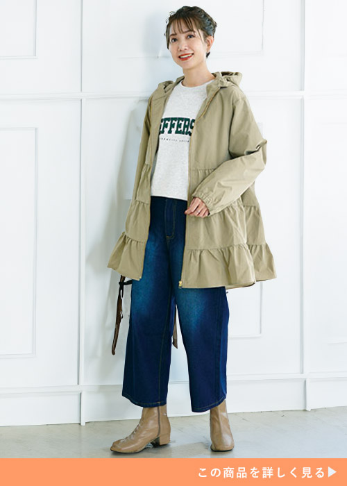 ホワイトトップスとデニムパンツのコーデにベージュのティアードブルゾンコートを羽織る女性