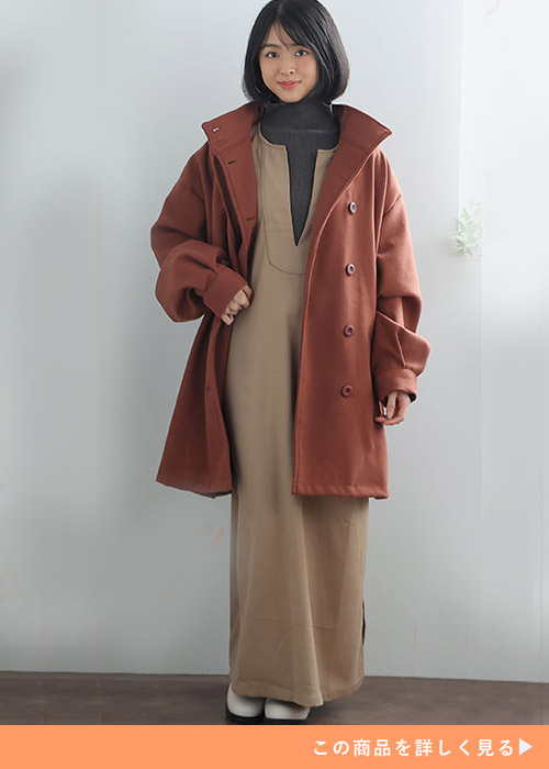 ベージュのワンピースにブラウンのAラインコートを羽織る女性