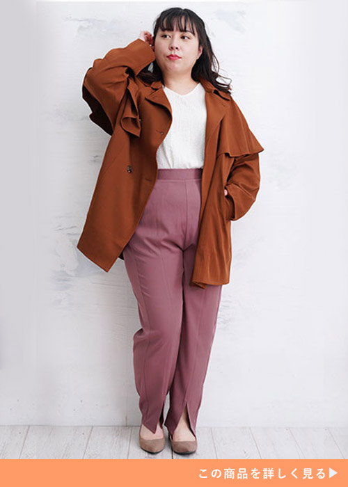 ホワイトトップスとローズカラーのパンツのコーデにブラウンのケープコートを羽織る女性