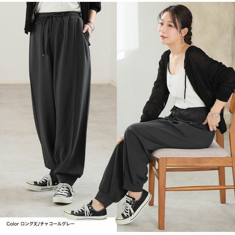 黒パンツに黒のカーデを羽織る女性