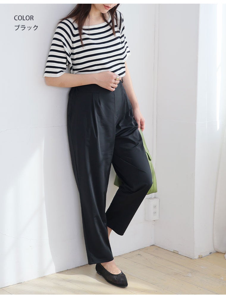 白黒のボーダートップス×黒のテーパードパンツを履く女性
