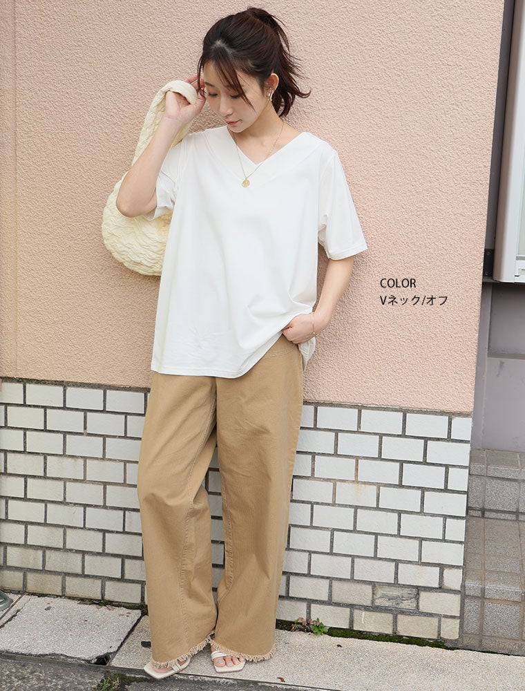 白のトップスを着て、ベージュのボトムを履く女性。