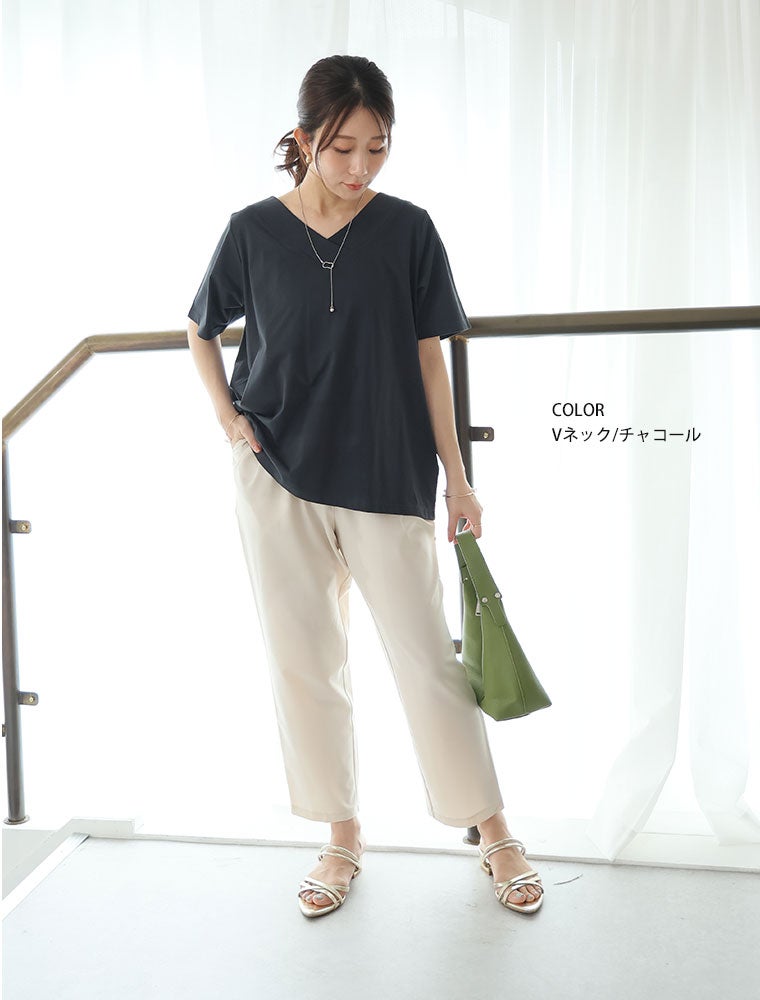 Vネックトップスに白のパンツを履く女性