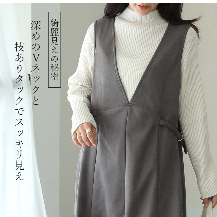 チャコールグレーのジャンスカとホワイトトップスを着る女性